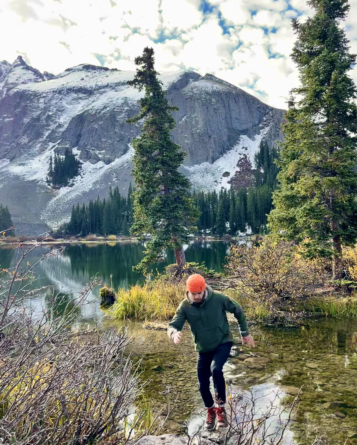 Rock-hopping a stream below a snow-dusted peak in the Colorado high country
